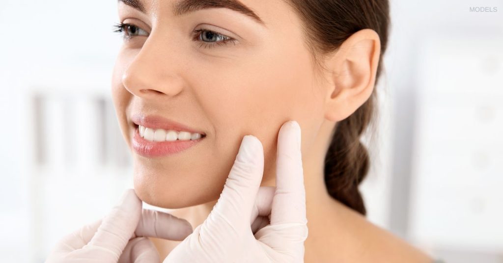 woman (model) having her face examined by a doctor.