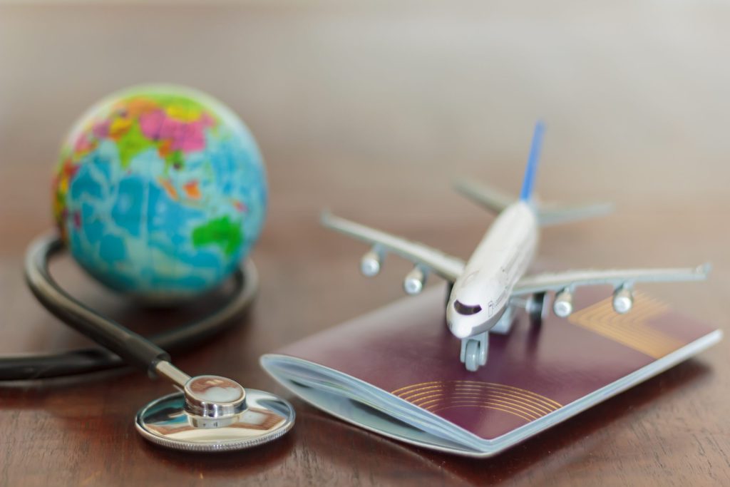 Stethoscope , passport document, toy airplane and globe
