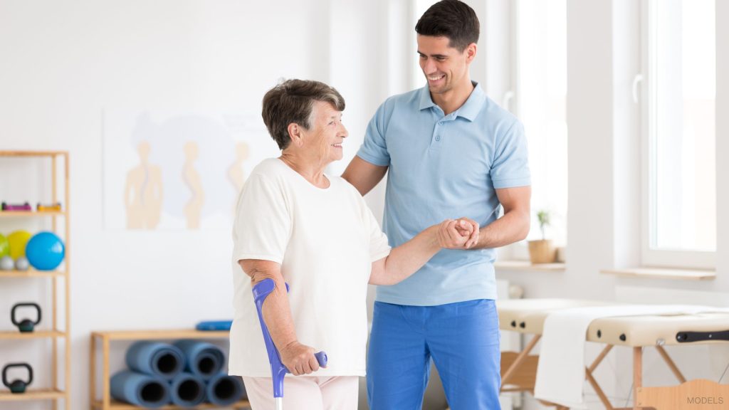 Elderly woman practicing mobility exercises with a therapist. (Models)