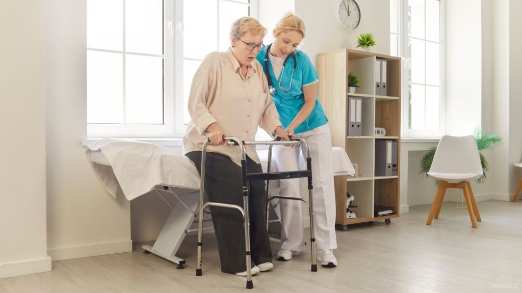 A doctor helping a woman walk after a hip replacement. (Models)